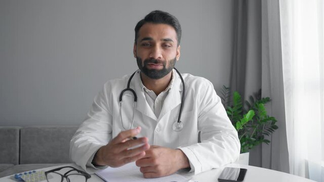 Adult indian male doctor wear white coat and stethoscope make online video call