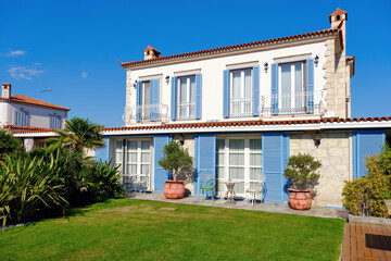 Fototapeta na wymiar Aegean or Mediterranean type luxury stone villa exterior with blue shutters