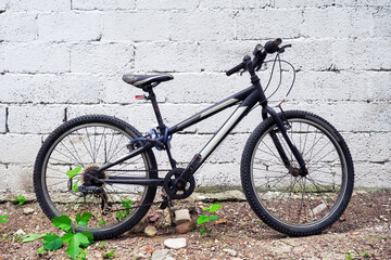 Black mountain bicycle at the garden against white wall background