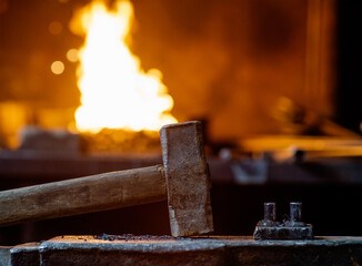 Blacksmith hammer stands on the anvil against the background of fire