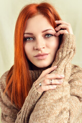 Portrait of a beautiful young red-haired woman wearing warm woolen sweater