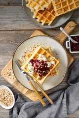 Homemade Belgian or Brussels waffles with Greek yogurt and lingonberry jam in a plate on a light gray wooden culinary background top view 