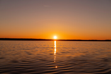 Obraz premium Water surface. View of a Sunset sky background. Dramatic gold sunset sky with evening sky clouds over the sea. View of a Crystal clear sea water texture. Landscape. Small waves. Water reflection