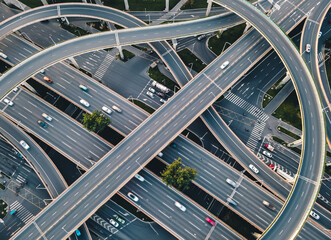 Modern development of traffic junctions and roads. Huge highway intersection with elevated ways in China. Motion blur vehicles moving along. Bright sunny evening in big metropolis city