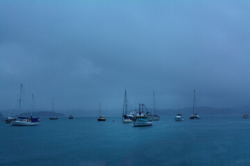 Heavy rain softens the lines of pleasure and fishing boats anchored in a small harbour