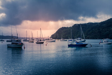 Small boats anchored in a harbour. Sunset on a stormy day