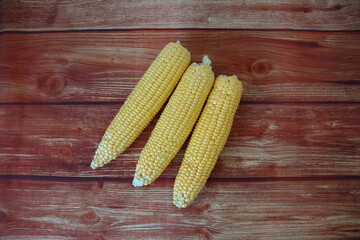 Cobs of fresh raw corn on wooden background