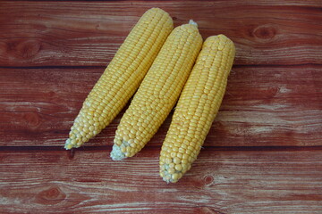 Cobs of fresh raw corn on wooden background