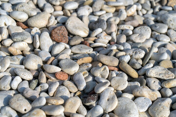 Pebble stones in different colors and sizes for background. Close up of bright white and grey stones at sunny beach