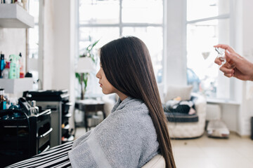 Young girl enjoying at hairstyle treatment while professional hairdresser gently working and cutting her hair.