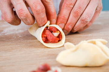 A man is holding a khinkali in close-up. Cook in the kitchen. The process of preparing a national dish.