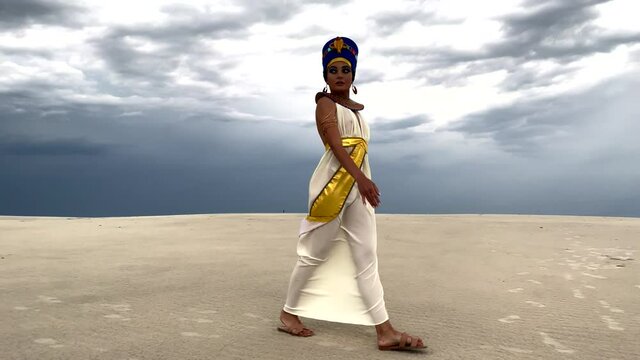 Woman in image of egyptian queen Nefertiti walks in desert.