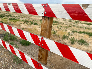 close up view of end of road red and white caution barrier warning blocking wood gate fence