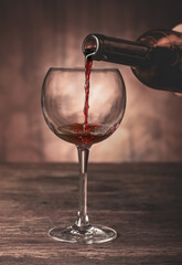 A wine glass that stands on the old table in which red wine is poured.