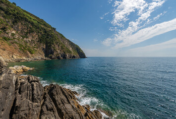 Coast and seascape (Ligurian Sea) in front of the small Riomaggiore village. Cinque Terre, National park in Liguria, La Spezia province, Italy, Europe. UNESCO world heritage site.