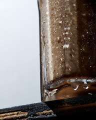 Cha Yen Thai iced tea brown-coloured in a glass, a half of glass on grey background bottom view