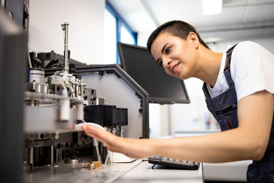 Professional female engineer servicing industrial machine in factory.