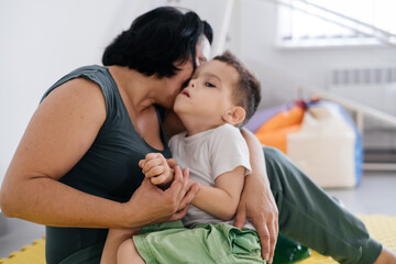 Mother playing with cute disabled child. Talking and communicating with cerebral palsy boy on the...
