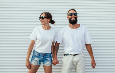 Young smiling couple in blank white t-shirts on street. Mockup for design.