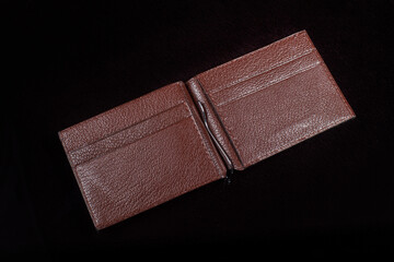 Open leather brown purse with pockets on a dark background.