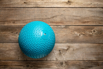 heavy rubber slam ball filled with sand on a rustic wooden deck, exercise and fitness concept
