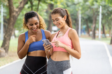 Young Women friends jogging together at park. Female runners listening to music while jogging.