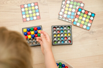 Childs hand on colorful wooden marbles. Color sequence logic game. A tool for pre-school and primary education. Montessori, brain exercise. Focus, patience and attention practice.