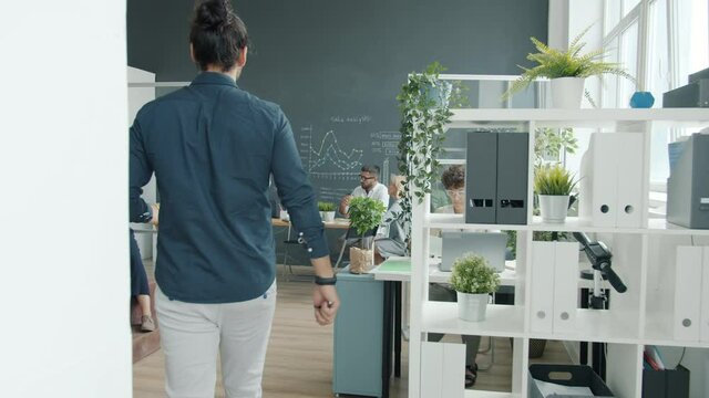 Middle Eastern man walking in office then watching young woman making presentation with interactive board. Business activities and workspace concept.