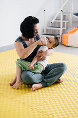 mother feeding, giving drinking water to disabled child with cerebral palsy during exercises....