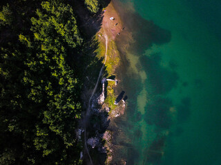 Aerial view of a tropical beach surrounded by trees and a blue lake from above by a drone.