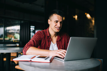 Skilled male copywriter with education textbook watching informative webinar on modern laptop...
