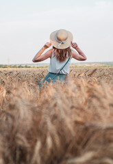 Happy woman with hat in summer field golden wheat, beautiful summer season. Girl enjoying life in colorful field ripe spikelets.