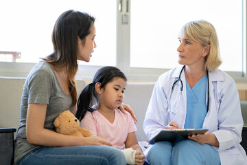 Fototapeta premium Pediatrician doctor examining little asian girl with a broken arm wearing a cast at hospital