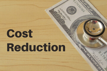 Stethoscope and money banknote with text COST REDUCTION.
