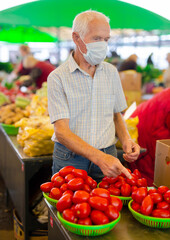 retired european man wearing medical mask protecting against virus buying tomatoes in market