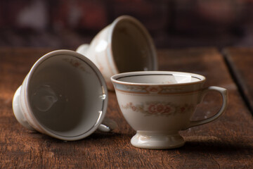 Porcelain cups, beautiful porcelain cups arranged on rustic wood, dark background, selective focus.