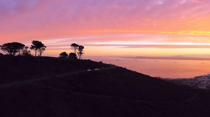 Aerial, drone panoramic of the top of Signal Hill silhouetted against the dawn sky and Table Bay in Cape Town, South Africa.