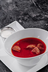 Homemade Russian, Ukrainian and Polish national soup - red borscht made of beetroot, vegetables and meat with sour cream. On textured dark background . High quality photo