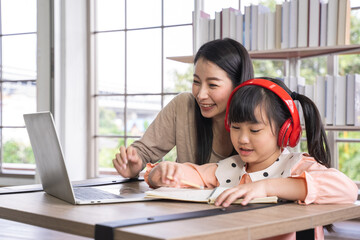 Home schooling learning at home during virus pandemic. asian woman with her daughter in the living room , wearing surgical face masks to protect them from the virus.