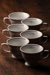 Porcelain cups, beautiful porcelain cups geometrically arranged on rustic wood, dark background, selective focus.