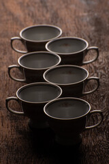 Obraz na płótnie Canvas Porcelain cups, beautiful porcelain cups geometrically arranged on rustic wood, dark background, selective focus.