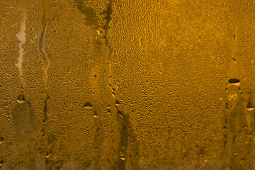 texture of fogged wet glass window in a room with warm light. horizontal