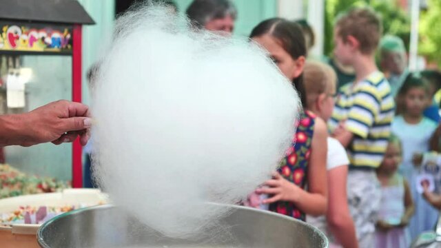 The process of making cotton candy outdoors for children.
