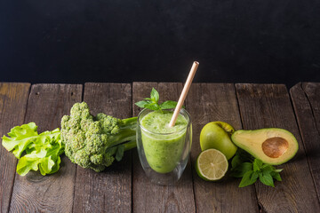 Fresh green smoothie in glass on wooden table, closeup.  Detox diet concept: green vegetables on...