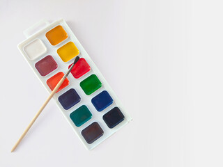 Watercolor paints and brush on a white background