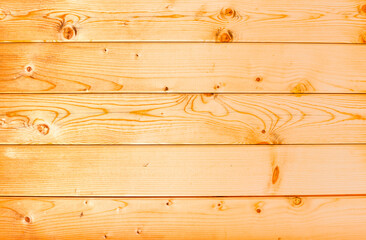 Naklejka premium The texture of wood on the wall of a house made of planed boards. Orange wood wall