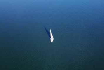 Fototapeta na wymiar Aerial view of a white yacht with a sail. Ship in the blue sea