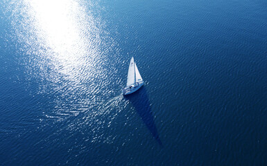 Aerial view of a white yacht with a sail. Ship in the blue sea