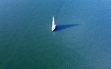 Aerial view of a white yacht with a sail. Ship in the blue sea