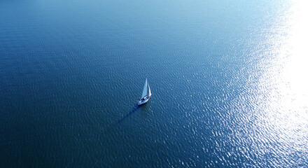 Aerial view of a white yacht with a sail. Ship in the blue sea